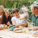 Family sitting in the yard. Mother and little daughter near the house. Big family on a picnic